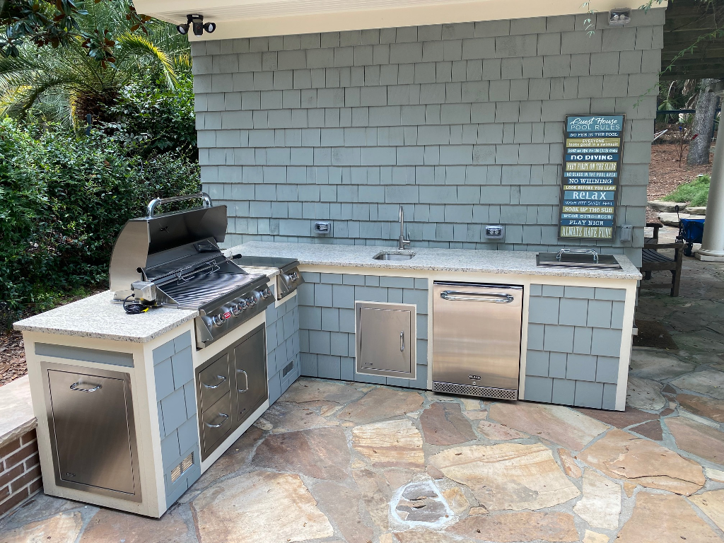 outdoor kitchen with propane grill, burner, sink, refrigerator, ice bin, trash receptacle
