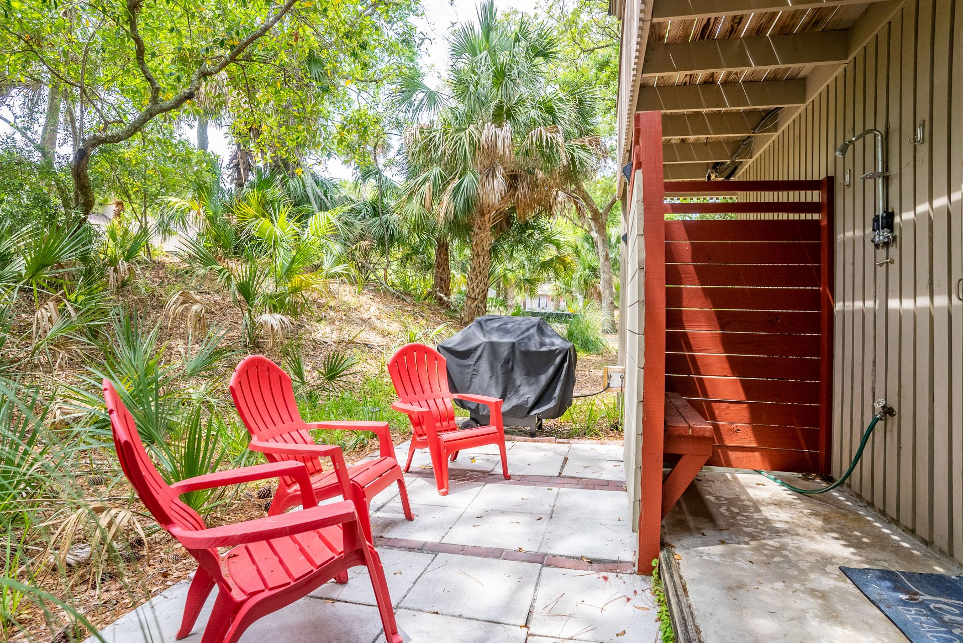 Outside heated shower with nearby adirondack chairs and grill 